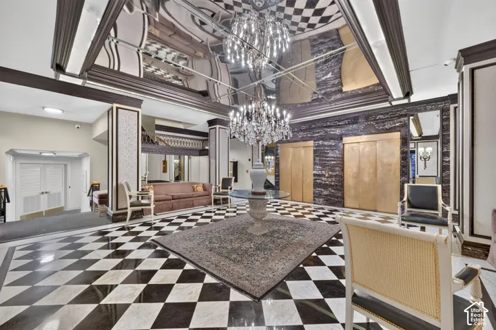 Black and white checkerboard flooring, two elaborate crystal chandeliers, mirrored ceiling, and gold-toned elevator doors