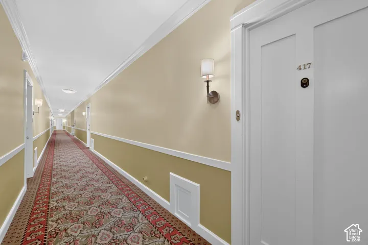 Long hallway featuring a patterned runner carpet, two-tone painted walls, and wall sconces