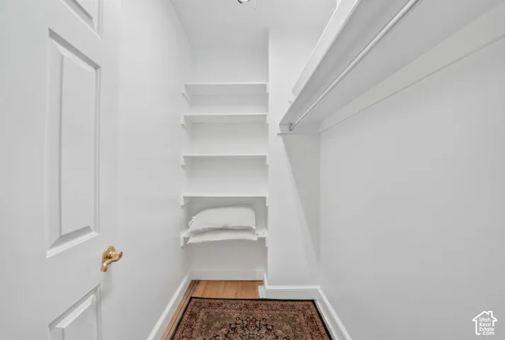Compact hallway with rich wood-finish flooring, white painted walls, and built-in shelving providing storage solutions