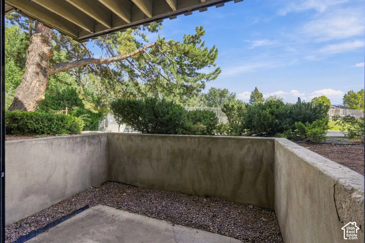 Outdoor patio with concrete retaining walls, gravel landscaping, and mature trees