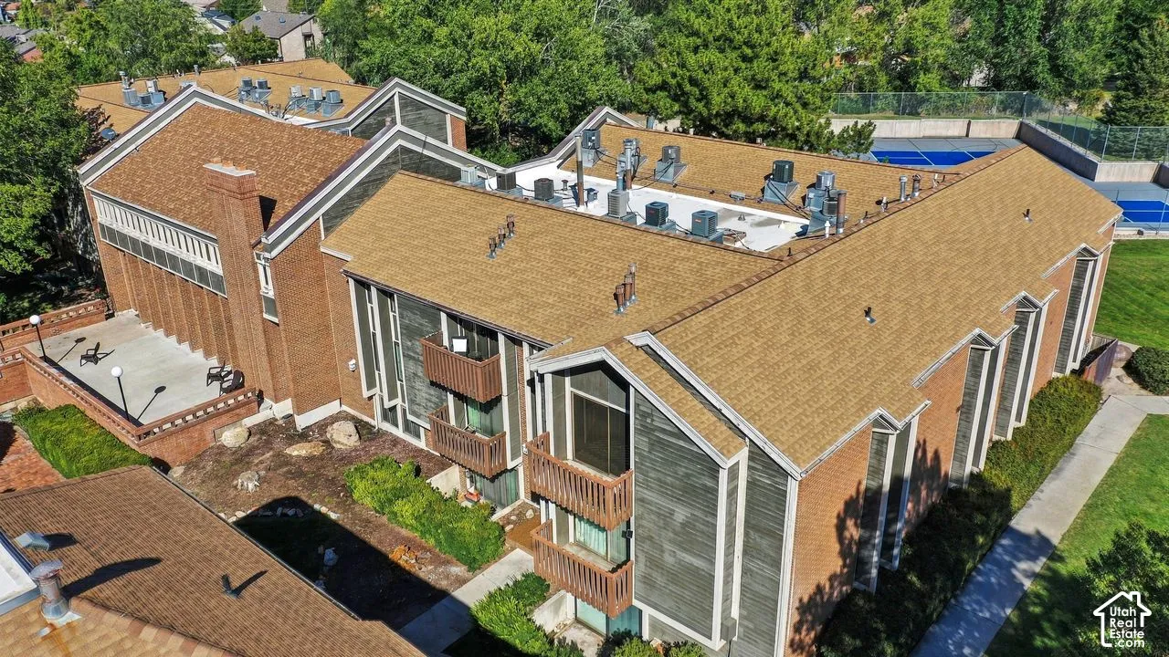 Multi-level building with a brown shingle roof, brick exterior, and multiple balconies