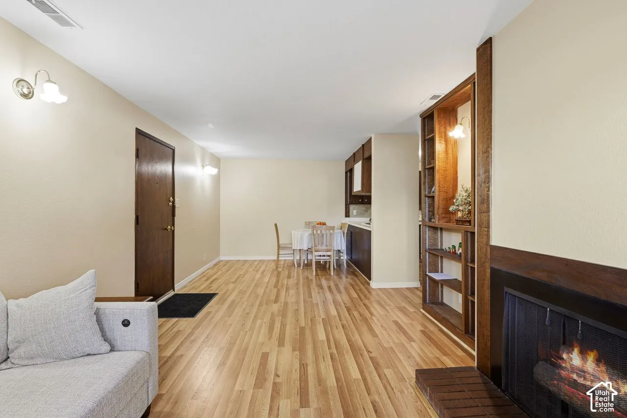 Wood-finish flooring, built-in shelving, sconce lighting, and a dark-toned fireplace with a brick hearth