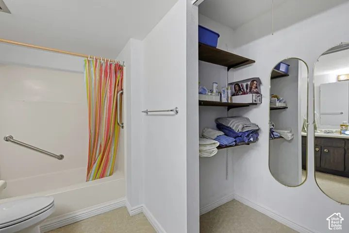 Built-in shelving, white bathtub with grab bars, and a wall-mounted towel bar