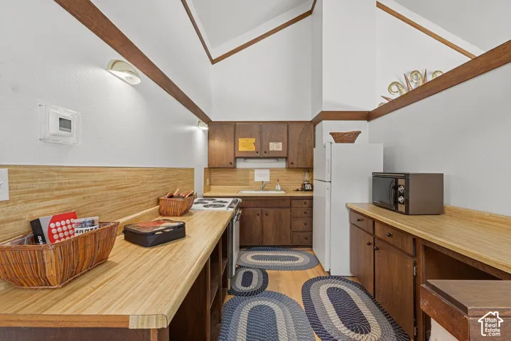 Club house Kitchen featuring wood-finish countertops, wood cabinetry, and a vaulted ceiling with exposed wood beams