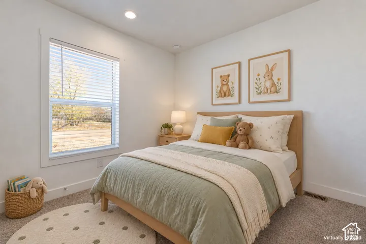 Recessed lighting, window with horizontal blinds, wood-finish bed frame, light-toned carpeting, and a built-in baseboard