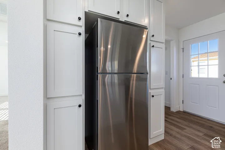 Stainless steel refrigerator integrated with white shaker-style cabinetry featuring black hardware