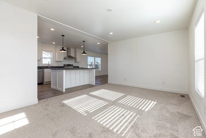 Open-concept living area with neutral carpet and recessed lighting