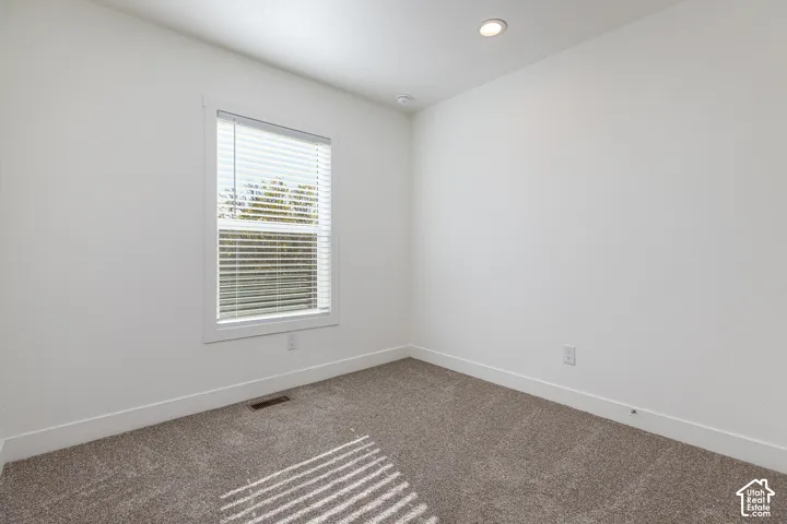 Recessed ceiling light, neutral carpet flooring, white window blinds, and white trim