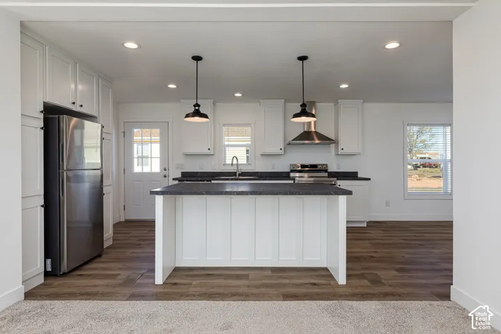 Kitchen featuring an island, stainless steel appliances, wood-finish flooring, recessed lighting, and pendant lighting