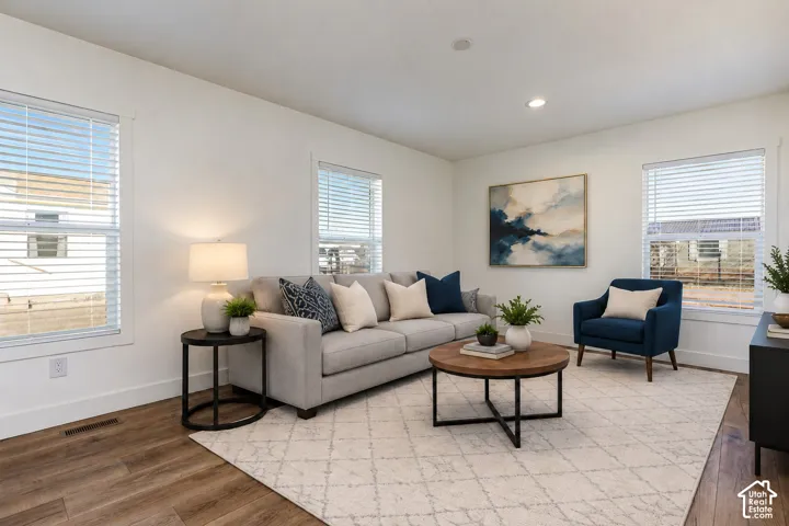 Recessed ceiling lighting, wood-finish flooring, multiple windows with blinds, and white walls