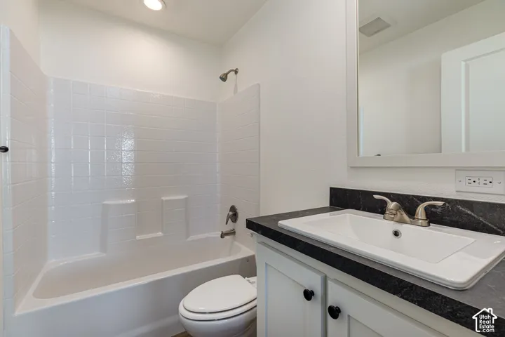 White vanity with a dark stone-finish countertop, undermount sink, and brushed nickel faucet