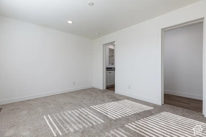 Primary Bedroom Recessed lighting, plush carpet flooring, white walls, and two open doorways