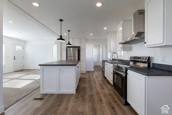 Kitchen featuring white cabinetry, dark countertops, a stainless steel appliance suite, and wood-finish flooring