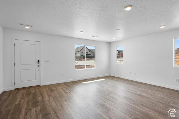 Wood-finish flooring with white walls and recessed ceiling lighting
