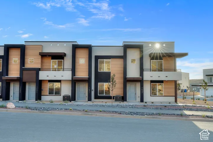 Contemporary townhouse exterior with a flat roofline, multi-textured facade including wood-finish siding, and integrated balconies