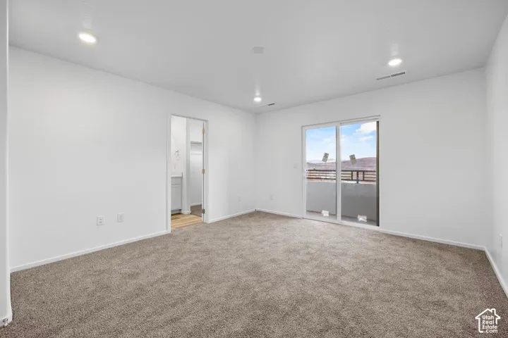 Recessed lighting, light-colored walls, sliding glass door, neutral-toned carpet, and balcony access