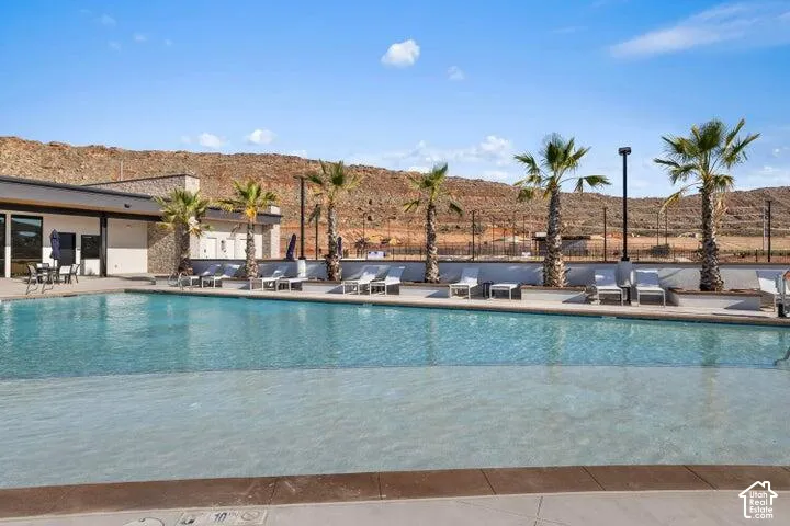 Expansive outdoor swimming pool with a shallow entry area, surrounded by a paved deck and multiple lounge chairs