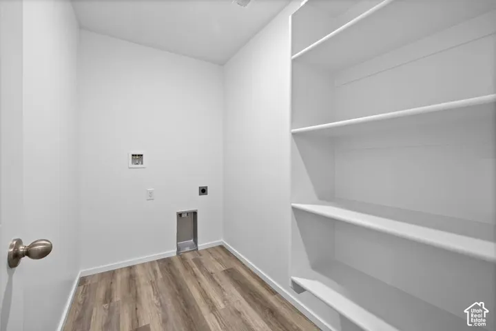 Laundry room with wood-finish flooring and integrated shelving