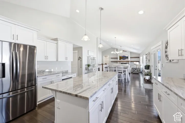 Kitchen featuring a large island with stone countertop, white cabinetry, stainless steel refrigerator, and wood-finish flooring