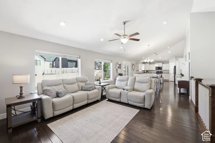 Expansive living space featuring rich wood-finish flooring, vaulted ceilings, and recessed lighting