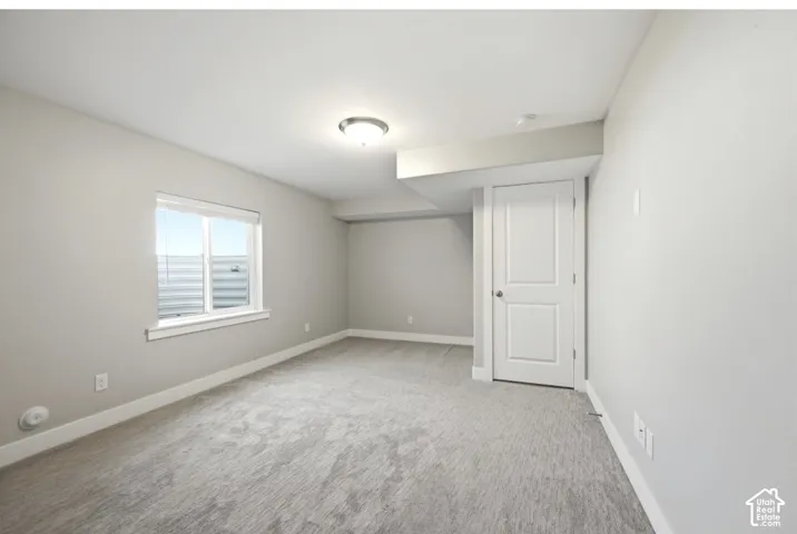 Light gray wall paint, gray patterned carpeting, white trim, recessed window, and white interior door with a silver knob