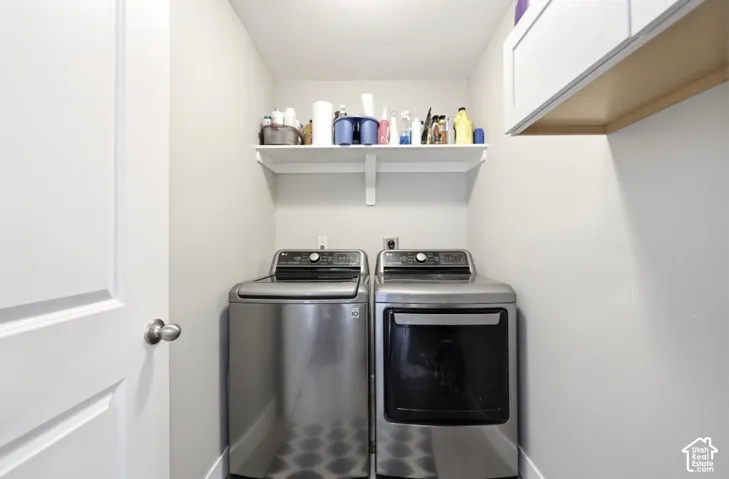 Utility area featuring a white shaker-style cabinet, a wall-mounted white shelf, and a light-toned ceiling