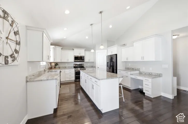 Kitchen featuring white cabinetry, light-toned countertops, a center island with pendant lighting, dark wood-finish flooring, and recessed ceiling lights