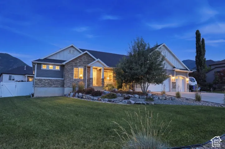 Stone and siding exterior with a pitched roofline, an attached two-car garage, and a landscaped front yard with a paved driveway