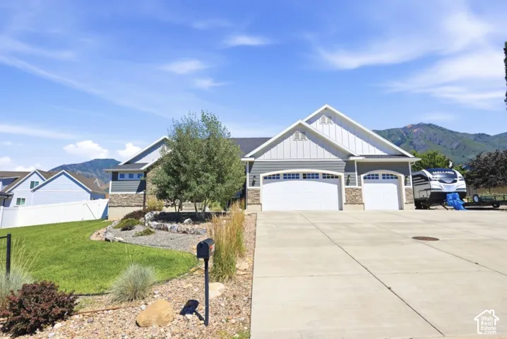 Exterior featuring a two-car garage, stone and siding facade, and a large concrete driveway
