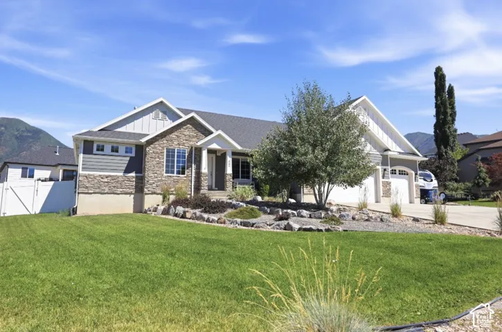 Stone facade with complementary siding, pitched roofline, attached two-car garage, and a landscaped rock garden