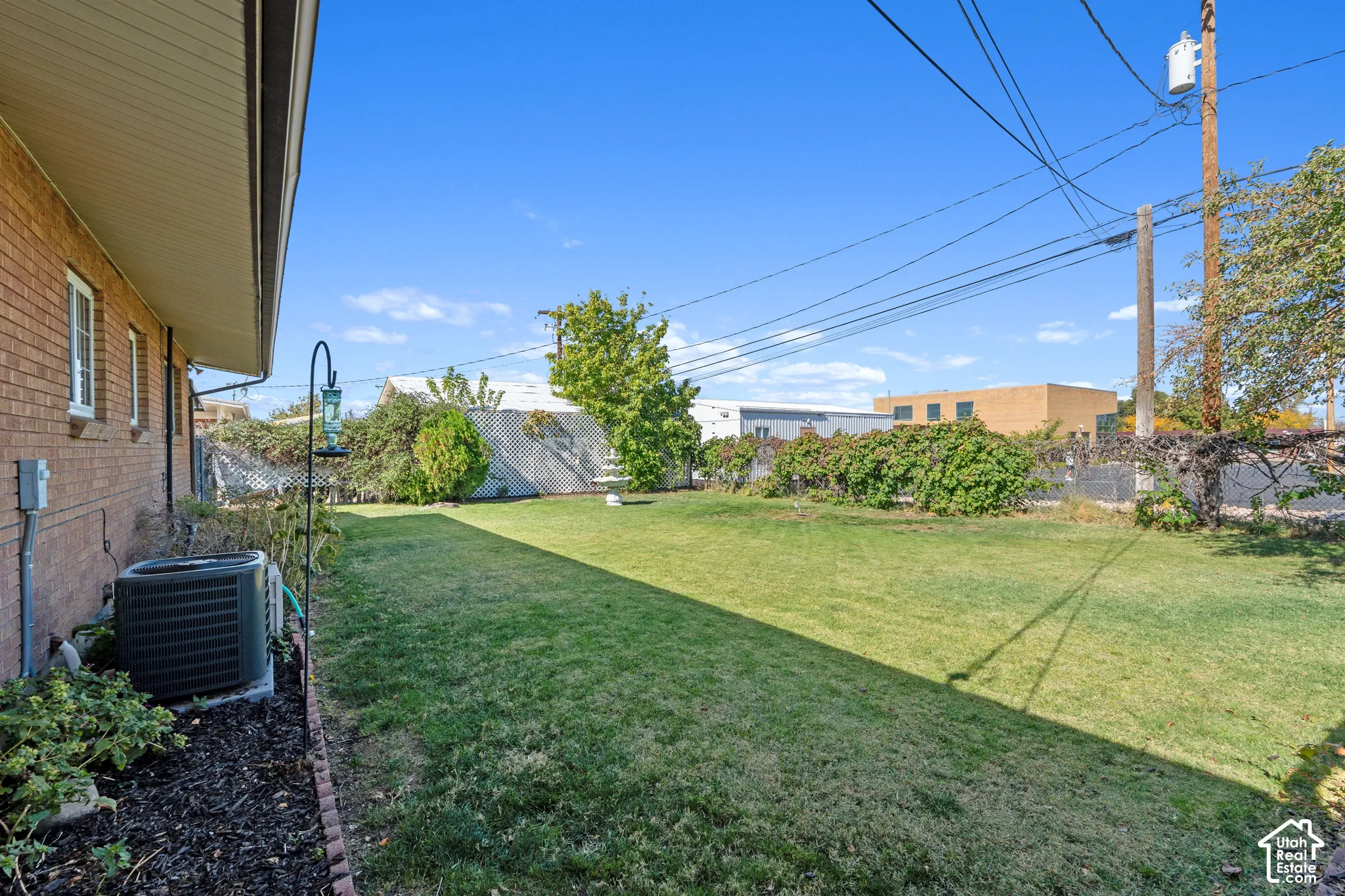 Expansive lawn area with mature perimeter landscaping and new air conditioning unit