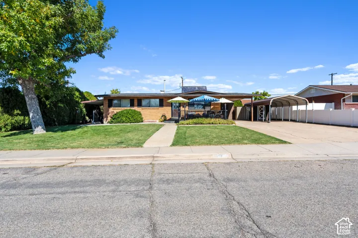 Brick-front single-story residence with a covered entry, established landscaping, and a large driveway