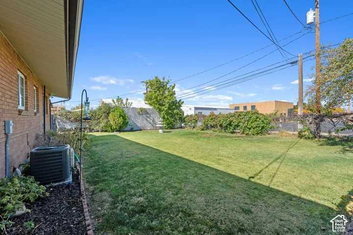 Expansive lawn area with mature perimeter landscaping and new air conditioning unit