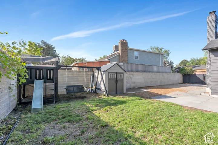 Expansive backyard with a manicured lawn, concrete retaining wall, and an outdoor storage shed