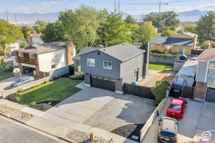 Modern two-story exterior with dark gray siding, an attached two-car garage, paved driveway, and manicured landscaping