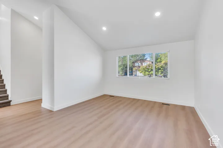 Expansive living area featuring wood-finish flooring, recessed lighting, and a large multi-pane window