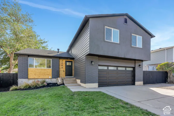 Contemporary exterior featuring dark gray siding, brick accents, and a two-car garage