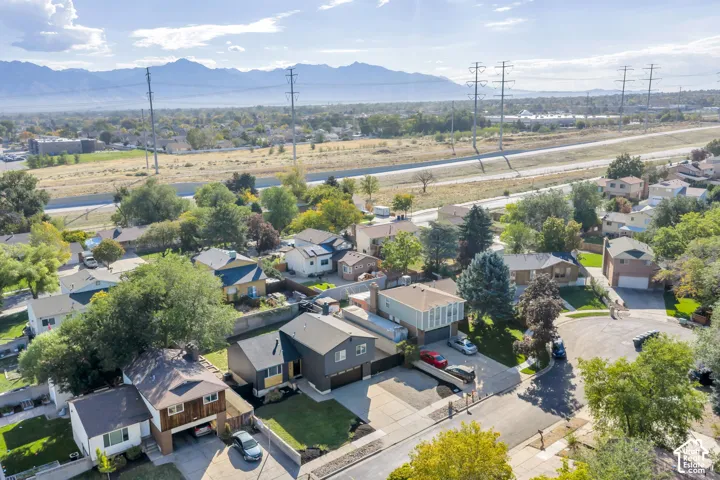 Residential neighborhood with mature trees, mountain backdrop, and varying architectural styles
