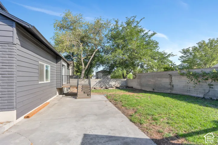 Exterior featuring horizontal siding, brick accents, concrete patio, and a grass area