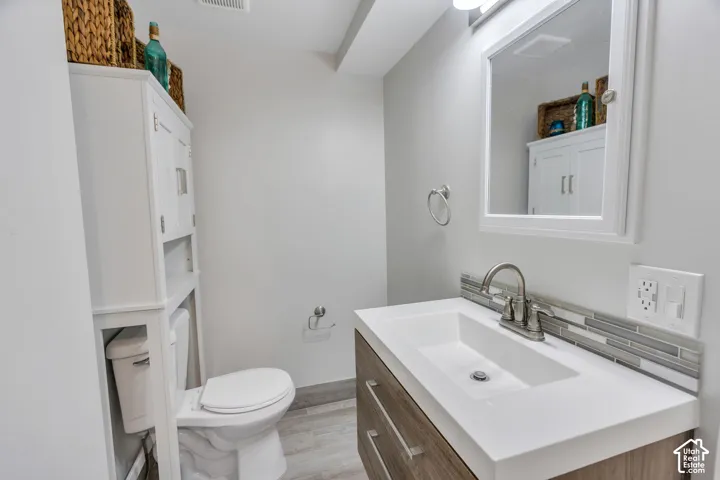Wood-finish vanity with an integrated rectangular sink, brushed nickel faucet, and a tiled backsplash
