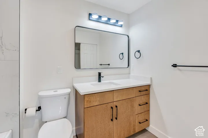 Modern vanity with a light wood-finish base, integrated white sink, and dark hardware