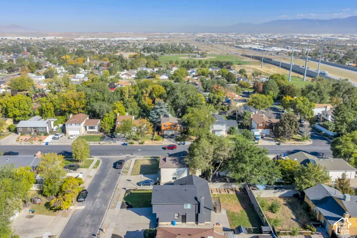 Aerial perspective showcasing a residential neighborhood with established trees, paved streets, and a distant mountain range