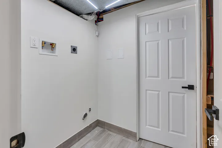 Laundry area with light-toned wall paint and wood-finish tile flooring