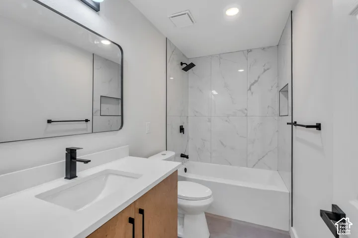 White countertop vanity with wood-finish cabinetry, rectangular sink, and matte black faucet
