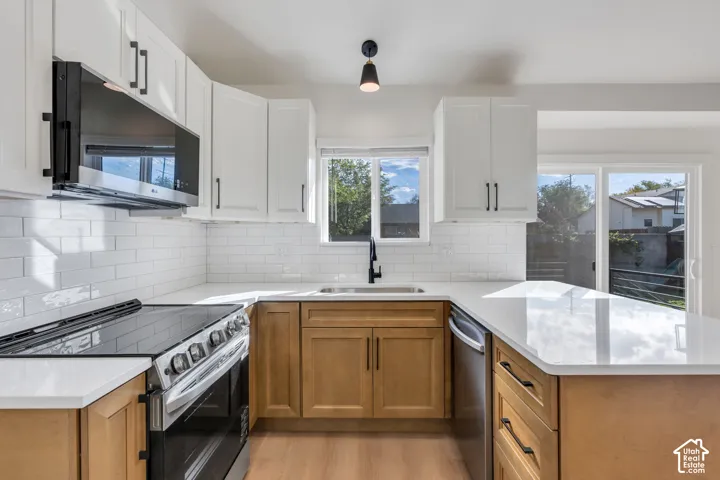 Contemporary kitchen featuring white shaker upper cabinetry and wood-finish lower cabinetry, white subway tile backsplash, and light-toned countertops