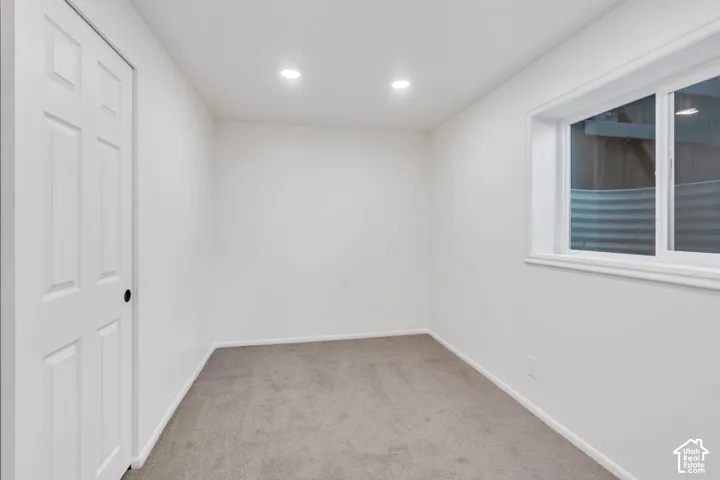 Recessed lighting, white trim, white walls, light-colored carpeting, and a window with a white frame