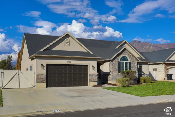 Stucco and stone facade with a dark gray shingle roof