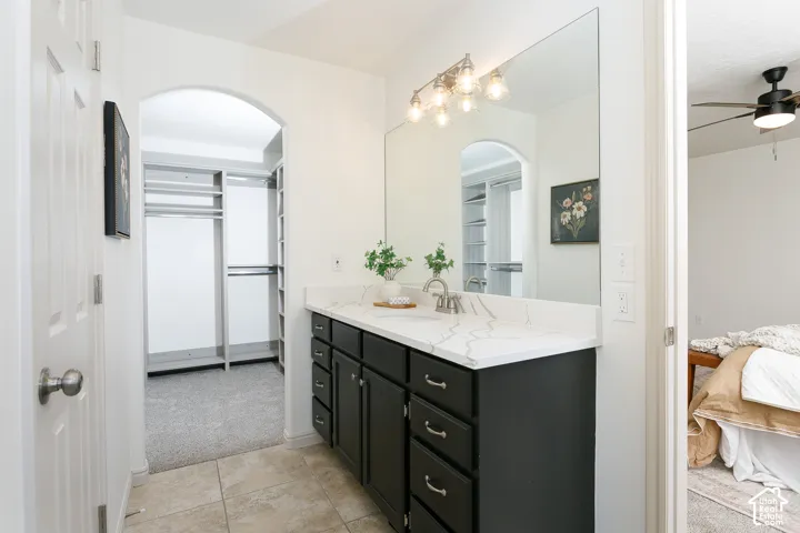 Vanity with dark cabinetry and a white countertop, featuring a single basin and a chrome faucet