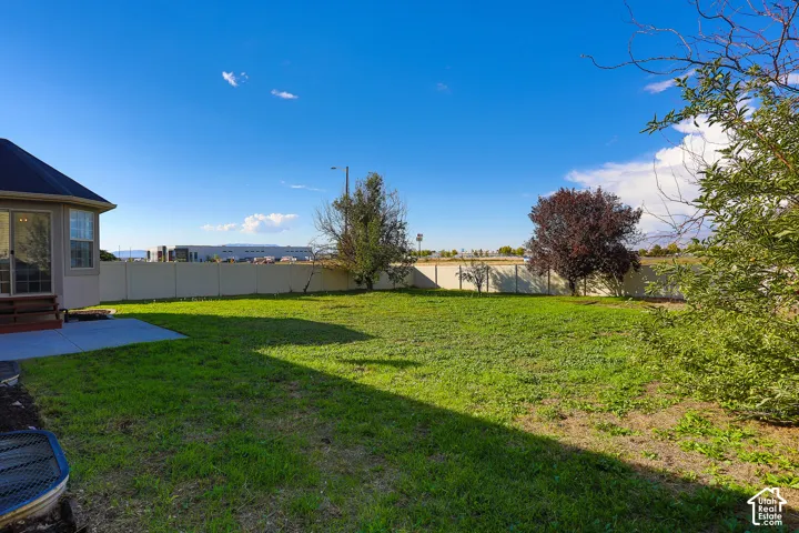 Expansive backyard with a manicured lawn, a large concrete patio, and a privacy fence