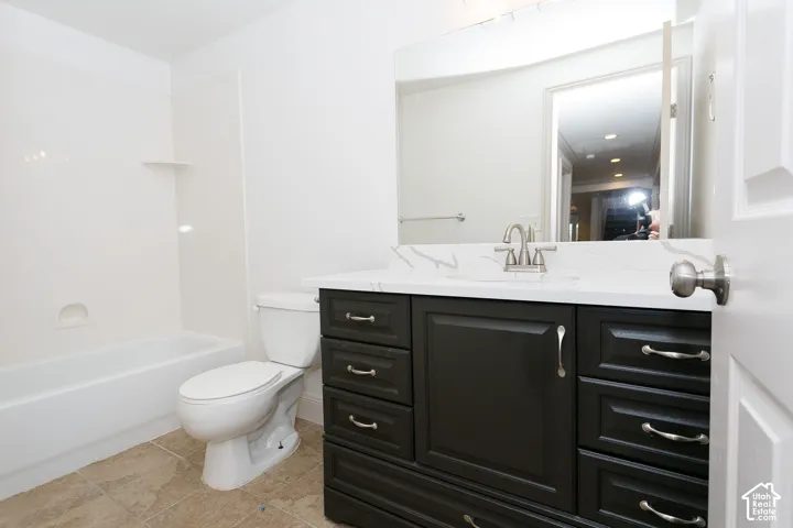 White bathtub with integrated shelving, dark wood-finish vanity with drawer storage, white countertop with veining, and brushed nickel hardware